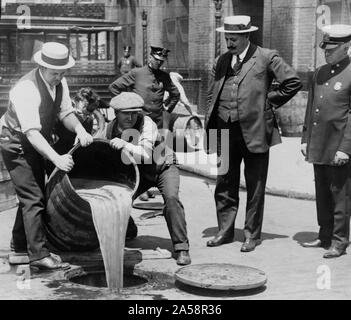 New York City Stellvertretender Polizeichef John A. Leach, rechts, beobachten Agenten gießen Schnaps in die Kanalisation nach einer Razzia auf dem Höhepunkt der Prohibition. Verbot in den Vereinigten Staaten konzentrierte sich auf die Herstellung, Transport und Verkauf von alkoholischen Getränken; jedoch Ausnahmen waren für medizinische und religiöse verwendet. Alkoholkonsum wurde nie nach den Bundesgesetzen illegal. Landesweites Verbot nicht in den Vereinigten Staaten beginnen, bis Januar 1920, wenn das achtzehnte Änderung der US-Verfassung in Kraft. Die 18. Änderung wurde 1919 ratifiziert. Stockfoto