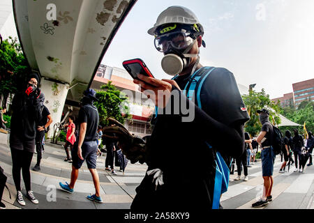 Ein Hong Kong Demonstrant das Tragen einer Gasmaske schaut auf sein Handy auf den Straßen von Hong Kong Stockfoto