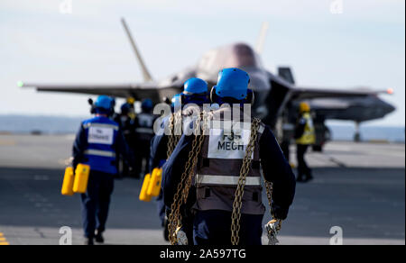 191017-N-QI 061-1340 ATLANTIK (Okt. 2010), 17, 2019) Segler zugeordnet, HMS Queen Elizabeth (RO8) tragen Ketten über den Flight Deck während der Flugbetrieb in den Atlantischen Ozean. HMS Queen Elizabeth ist derzeit zur Unterstützung der WESTLANT 19 die Mission Planning bereitgestellt, die bewaffnung von Flugzeugen mit Hilfe des Schiffes hoch automatisierten Waffe Handling System, Fliegende Missionen und Debriefing nach Abschluss. Der erste Einsatz für HMS Queen Elizabeth 617 Squadron und ein Geschwader der US Marine Corps Lightning Jets ist im Jahr 2021 zu nehmen. (U.S. Marine Foto von Massenkommunikation S Stockfoto