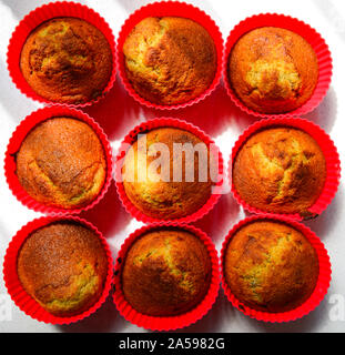 Frisch gebackene Muffins in rotem Silikon Cups in der Küche Sonnenlicht Stockfoto