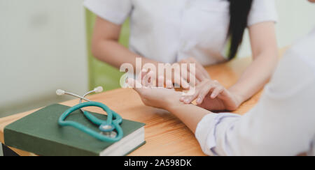 7/8 shot der weiblichen Doktor ihr Patient Puls mit der Hand prüfen, in der Klinik Zimmer Stockfoto