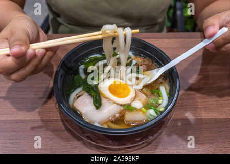 Nahaufnahme der menschlichen Hand picking Udon-nudeln von Stäbchen Stockfoto