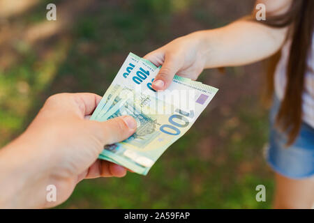 Männliche Hand Geld einem Kind closeup, Hundertstel Euro-Banknoten Stockfoto