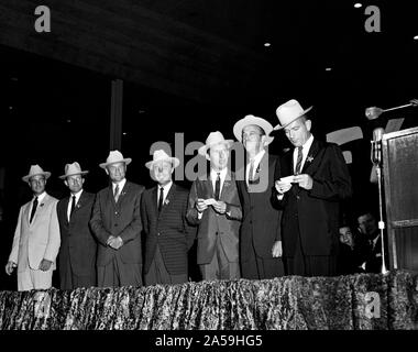 (4 Juli 1962) - - - Die ursprünglichen sieben Mercury Astronauten, jedem tragen Neue cowboyhüte und ein Abzeichen in der Form eines Sterns, abgebildet auf der Bühne an der Sam Houston Coliseum. Eine große Menschenmenge war an Hand sie zu Houston, Texas begrüßen zu dürfen. Zu recht sind Astronauten M. Scott Carpenter, L. Gordon Cooper jr., John Glenn Jr., Virgil Grissom, Walter I. M. Schirra jr., Alan B. Shepard, Jr., und Donald K. Slayton verlassen. Senator John Tower (R-Texas) ist ganz rechts im Hintergrund zu sehen. Stockfoto