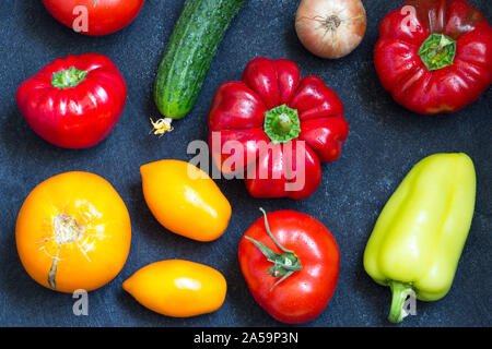 Frische ganze Gemüse aus neuer Ernte auf dunkelblauem Hintergrund. Gewaschen, Paprika, Tomaten, Zwiebel und Gurke auf Tisch. Ansicht von oben. Close-up. Rohe Nahrungsmittel Stockfoto