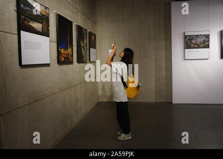 (191019) - JINGDEZHEN, Oktober 19, 2019 (Xinhua) - eine Frau besucht eine Fotografie Ausstellung während einer keramischen Messe in Jingdezhen, der ostchinesischen Provinz Jiangxi, Okt. 18, 2019. Die fünf Tage, 2019 China Jingdezhen International Keramik Messe eröffnet am Freitag, zieht fast 1.000 Porzellan Firmen aus dem In- und Ausland. (Xinhua / Zhou Mi) Stockfoto