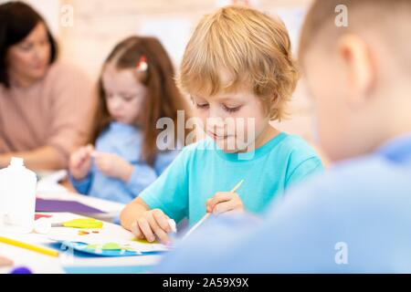 Kindergarten Kinder Kunst und Handwerk mit Lehrer in Kindertagesstätte Stockfoto