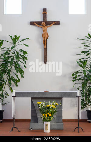 Der Altar der Katholischen Kirche, in einem klaren Design mit einigen grünen Pflanzen und einen Strauß gelber Blumen vor dem Altar. Es ist ein WOODE Stockfoto