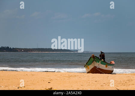 Grün, Weiß und Rot Fischerboot auf einen Sandstrand an einem sonnigen Tag mit einer Krähe saß auf dem Motor - Indien, Mamallapuram September 2019 Stockfoto