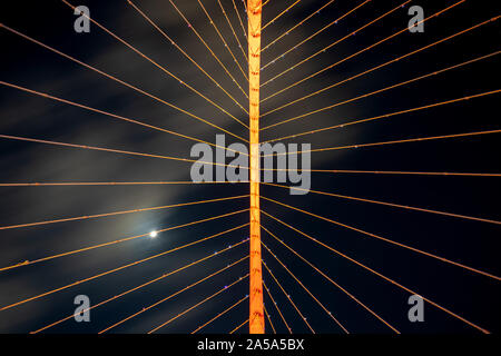 Eine abstrakte Sicht nach oben während der Nacht zeigt die Verkabelung einer Hängebrücke in ungewöhnlichen Aussehen. Diese Ansicht erzeugt eine vertikale Trennlinie Stockfoto