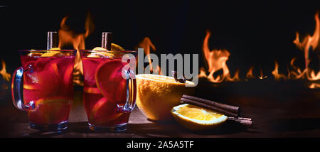 Zwei Tassen weihnachten Glühwein gegen einen Brand. Glühwein oder heißen Wein. Traditionelle Winter trinken. Panorama. Banner Stockfoto