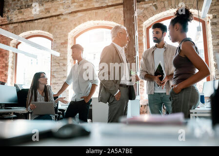 Büroalltag. Gruppe der modernen Menschen miteinander reden und diskutieren Geschäftsideen beim Stehen in der kreative Büro Stockfoto