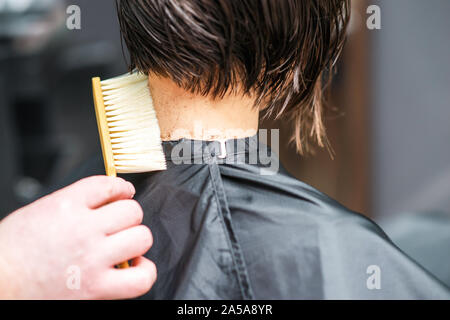 Friseur shakes Haar vom Nacken der Frau an Friseursalon Cut. Friseur Mensch ist Reinigung Schneiden der Haare am Hals der Frau im Beauty Salon. Haarschnitt, die im Salon. Stockfoto