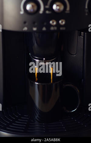 Köstliche Tasse Espresso aus einer heimischen Espressomaschine gegossen wird. Kaffee in einer Kaffeemaschine gegossen wird. Die Zubereitung von Kaffee zu Hause ist bereit Stockfoto