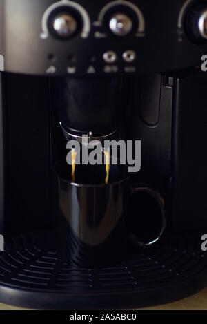 Köstliche Tasse Espresso aus einer heimischen Espressomaschine gegossen wird. Kaffee in einer Kaffeemaschine gegossen wird. Die Zubereitung von Kaffee zu Hause ist bereit Stockfoto