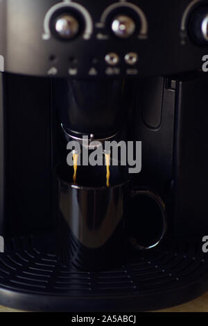 Köstliche Tasse Espresso aus einer heimischen Espressomaschine gegossen wird. Kaffee in einer Kaffeemaschine gegossen wird. Die Zubereitung von Kaffee zu Hause ist bereit Stockfoto