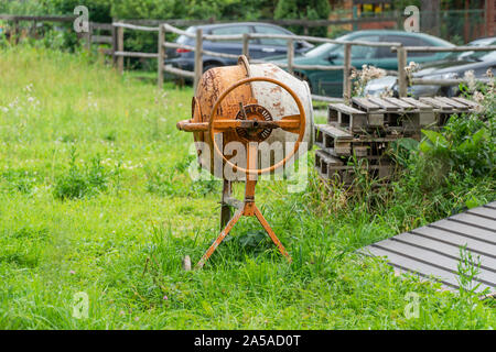 Alten rostigen Betonmischer steht auf dem Rasen im Hof Stockfoto