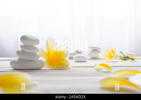 Gestapelte Steine weiß auf weißem Hintergrund mit gelben frangapani Blume - Lebensstil und alternative Health Concept Bild mit Kopie Platz für Text. Stockfoto