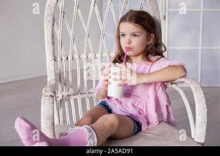 Schöne kleine Mädchen trinkt Milchshake durch Rohr Stockfoto