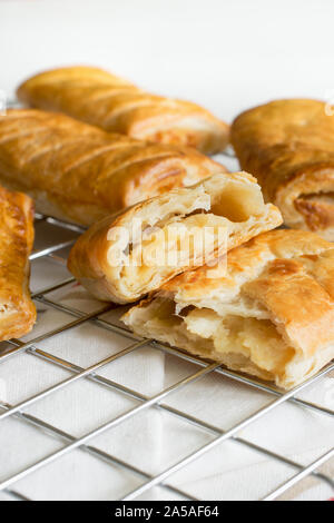 Herzhafte Käse und Zwiebeln Blätterteig Brötchen frisch aus dem Ofen Kühlung auf einem kochen Untersetzer eine vegetarische Alternative zu den üblichen Wurstbrötchen Stockfoto