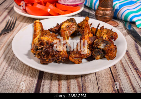 Lamm Rippen mit Gewürzen mariniert Gegrillte in einem Teller auf dem Tisch. Mit in Scheiben geschnittenen Tomaten, Paprika und Zwiebeln Stockfoto