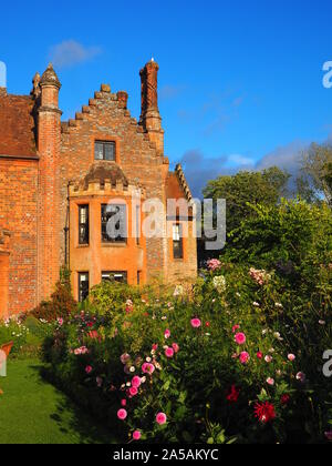 Portrait von chenies Herrenhaus aus Garten. schönem Wetter, blauer Himmel und alten Mauerwerk in der Sonne mit September blühenden Dahlien, Kosmos und Rosen. Stockfoto