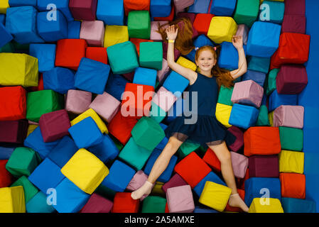 Süße kleine Mädchen liegt in Weiche Würfel, Spielplatz Stockfoto