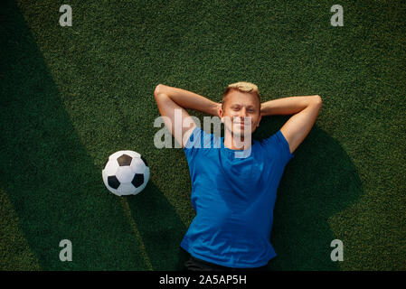 Männliche Fußballspieler mit Ball, die auf dem Gras Stockfoto