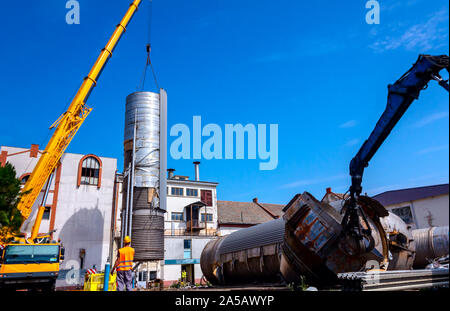 Lader Maschinen mit hydraulischer grappling Klaue und Kran sind die heavy metal Silo in industriellen Komplexes. Stockfoto