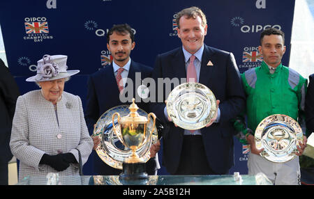 Königin Elizabeth II (links) neben gewinnendes Jockey Sean Levey (rechts) und gewinnende Trainer Richard Hannon (Mitte rechts nach König der Veränderung die Queen Elizabeth II Stakes gewonnen während QIPCO britische Champions Day in Ascot Pferderennbahn. Stockfoto