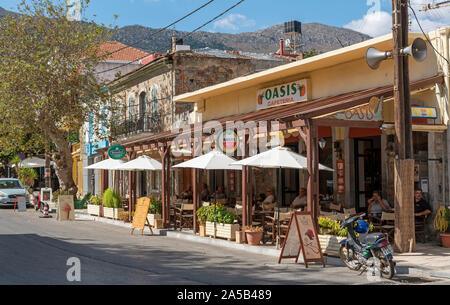 Neopolis, nördlichen Kreta, Griechenland. Oktober 2019. Eine Café-Bar auf die Alte Nationalstraße wie Fahren in Neopolis einen Kretischen historische Stadt. Stockfoto