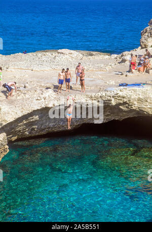 Mann in die Höhle von Poesie, einem berühmten natürlichen Pool, Roca Vecchia, Melendugno, Lecce, Apulien, Italien springen Stockfoto