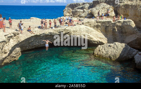 Mann in die Höhle von Poesie, einem berühmten natürlichen Pool, Roca Vecchia, Melendugno, Lecce, Apulien, Italien springen Stockfoto