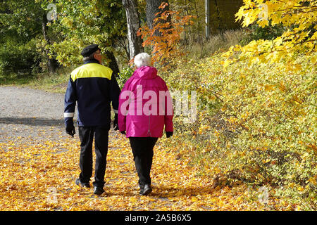 Turku, Finnland - 5. Oktober 2019: Älteres Paar zu Fuß auf dem Weg, Baum hat Blätter zu Gehweg fallengelassen. Lage: Insel Ruissalo Stockfoto