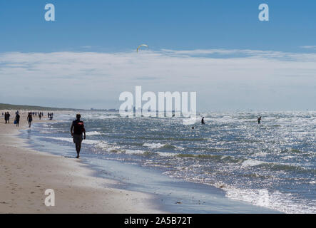 Vor der Skyline von Den Haag (Den Haag), Kitesurfer und Touristen genießen die stürmische Nordsee auf einem Strand von Katwijk, Niederlande. Stockfoto