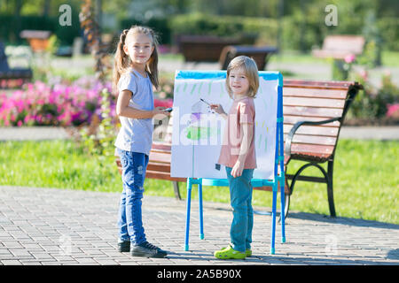 Ein Mädchen und ein Junge sind Zeichnen mit Farben auf einem großen Blatt Papier. Stockfoto
