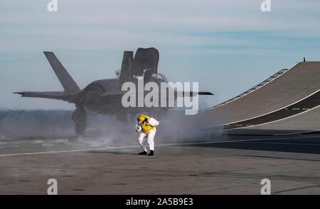 Die Royal Navy sailor reagiert als F-35B Blitz Stealth Fighter Aircraft startet von der Flight Deck der HMS Queen Elizabeth während des Flugbetriebs am 17 Oktober, 2019 in den Atlantischen Ozean. HMS Queen Elizabeth, ist das größte Kriegsschiff der Royal Navy gebaut und wird derzeit zur Unterstützung der Übung eingesetzten WESTLANT 19. Stockfoto