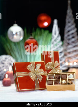 Luxus Geschenkboxen mit Goldband und Schokolade gegen verschwommenen Hintergrund Stockfoto