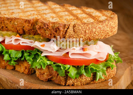 Handgefertigte Türkei Sandwich mit Tomate, Salat und Gurken, auf hölzernen Hintergrund, selektiver Fokus Stockfoto