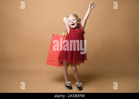 Ein junges Mädchen im roten Kleid und mit Einkaufstüten, Happy Shopping Stockfoto