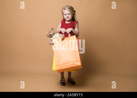 Ein junges Mädchen im roten Kleid und mit Einkaufstüten, Happy Shopping Stockfoto