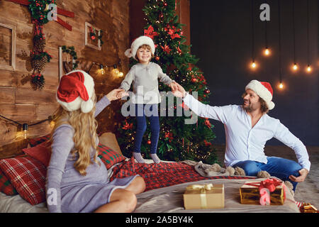 Lachende Kinder mit Eltern auf Bett in Weihnachten Stockfoto