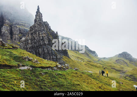Touristen don Regenmäntel bis zu Wanderung der Alte Mann von Storr, einem berühmten Felsen auf der Insel Skye, Schottland