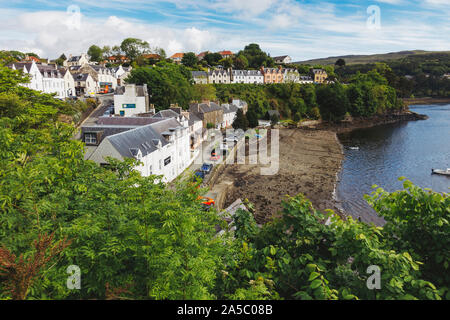 Peering über Baumwipfeln auf die bunten Häuser von Portree, von oben auf die Pauschale einen Hügel am Rande der Stadt in Schottland, Großbritannien Stockfoto