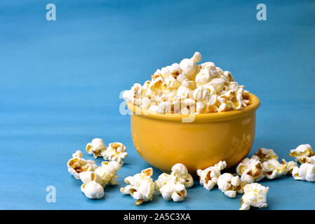 Popcorn in Schüssel mit Rosa unten mit Mais neben auf blauem Hintergrund Stockfoto