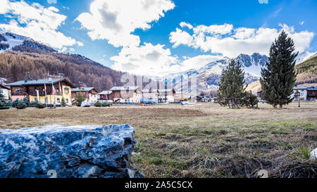 Big Rock und Wiese im Vordergrund, Dorf in den Fuß der Berge, Livigno ist eine kleine Stadt und Italienische Ski Alpin Center, Italien, Alpen Stockfoto