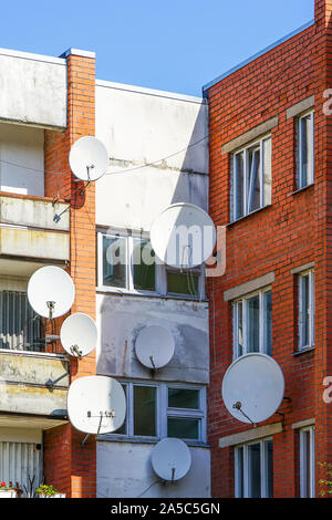 Viele weiße Parabol Satelliten Antenne Gerichte an der Wall von Suburban perfab Mehrfamilienhaus gehängt. Stockfoto