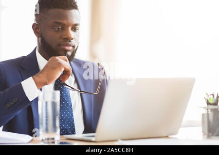 Der Mann im Anzug, der die Berichte auf Laptop Stockfoto