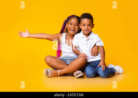 Portrait von niedlichen kleinen schwarzen Mädchen und Junge sitzt auf dem Boden und Kuscheln Stockfoto