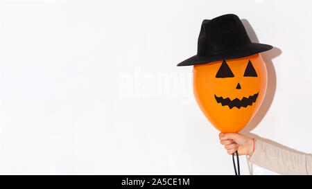 Orange Balloon mit Zeichnung Gesicht und in hat in der Frau die Hand Stockfoto